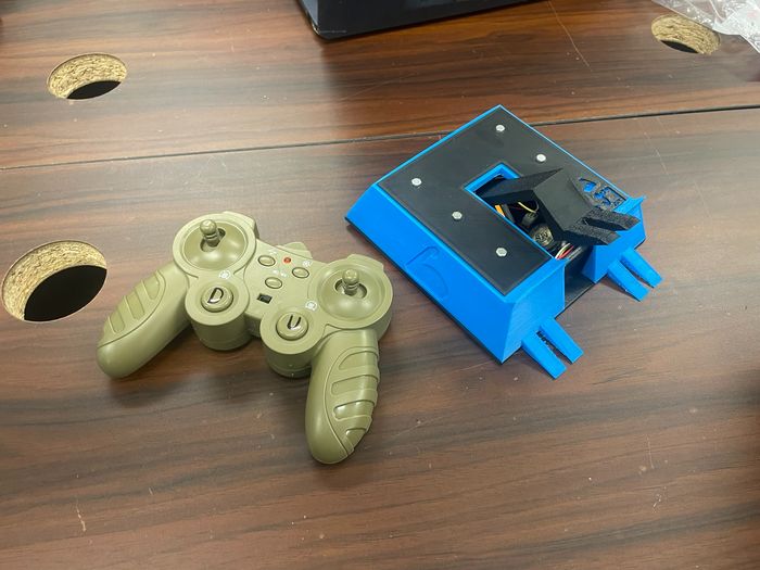 Big Guy, a blue and black 3D printed combat robot with a flipper, beside its controller