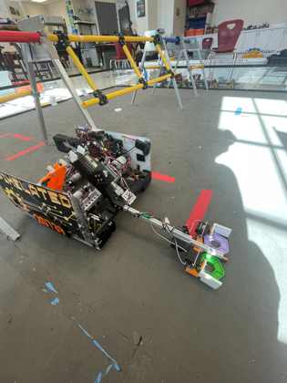 Team 20739's robot with a long arm gripping a green and a purple pixel
