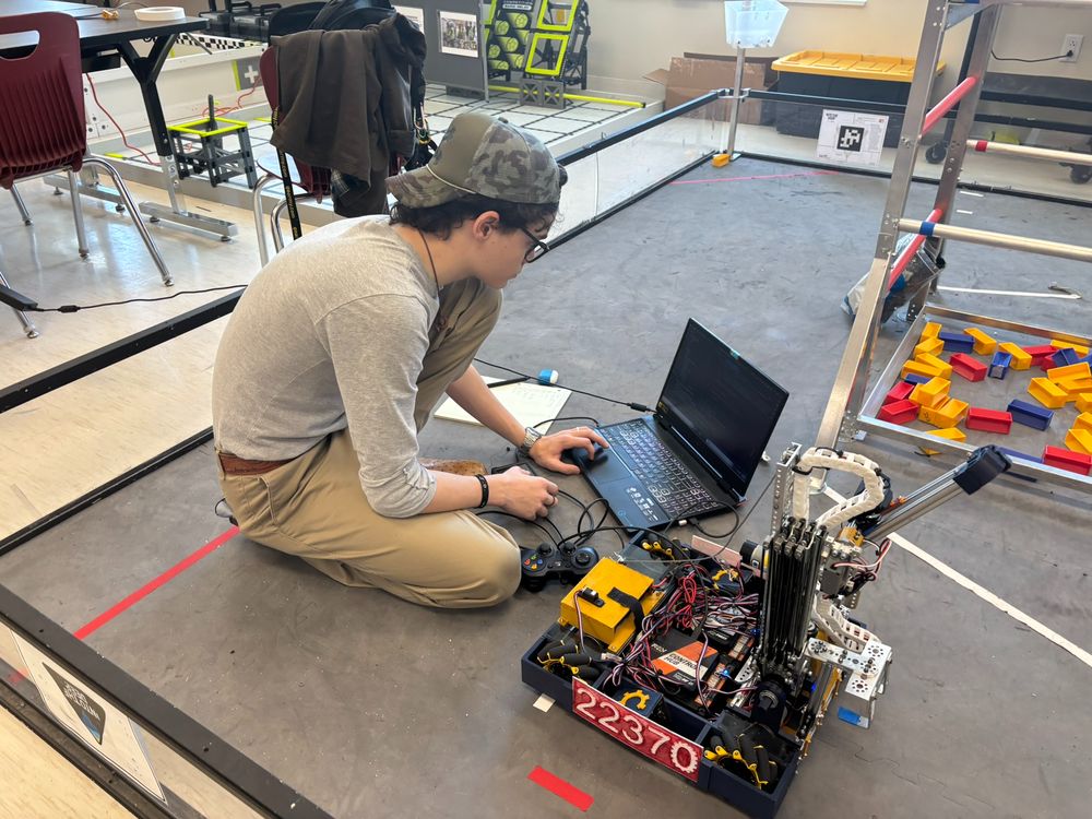 James at a laptop on the field floor tuning the Squeaker robot, team number 22370